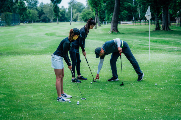Golf zetten. Twee jonge dames oefenen met putten - Foto, afbeelding