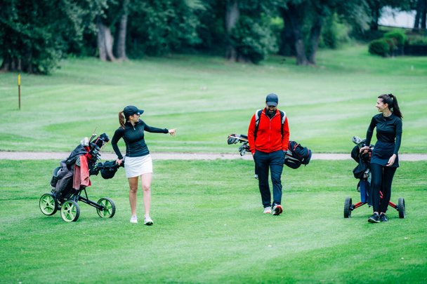 Entrenamiento de golf. Dos señoritas con instructor de golf que tienen una lección en un campo de golf - Foto, Imagen