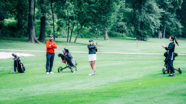 Entrenamiento de golf. Dos señoritas con instructor de golf que tienen una lección en un campo de golf - Foto, Imagen