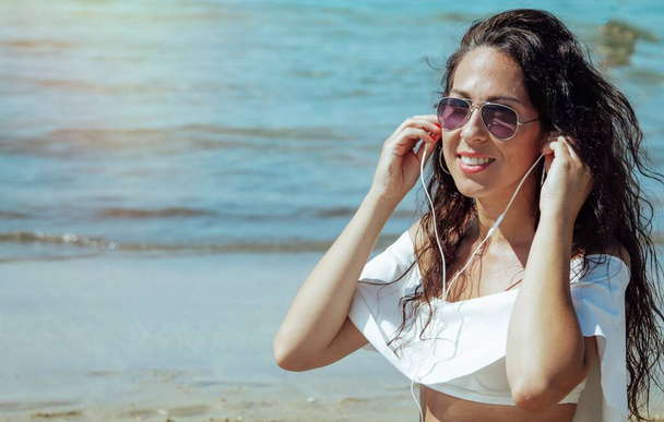 woman on the beach with mobile phone and headphones - Foto, afbeelding