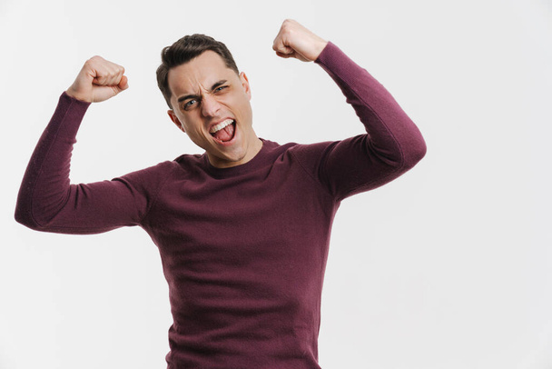Young brunette man screaming and making winner gesture isolated over white background - Фото, зображення