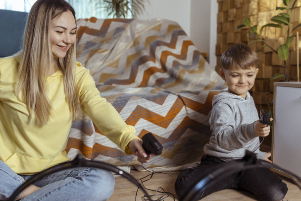 Mom and little son play racing on the carpet at home, have fun and hug. Single mother raises her son by playing cars - Φωτογραφία, εικόνα