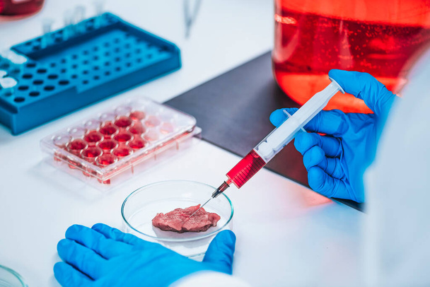 Científico inyectando hormona del crecimiento en una muestra de carne en laboratorio - Foto, imagen