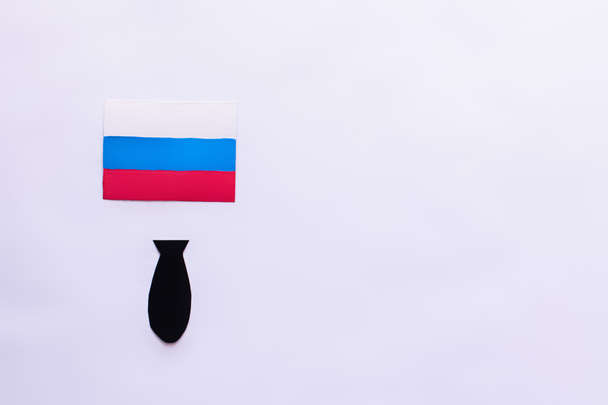 Pohled shora na ruskou vlajku a papírovou bombu na bílém pozadí s kopírovacím prostorem, válka v ukrajinském konceptu  - Fotografie, Obrázek