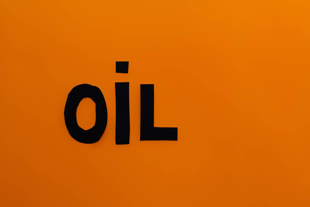 Vista superior de la palabra aceite de papel sobre fondo naranja  - Foto, imagen