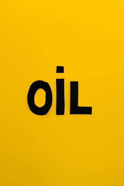Vista superior da palavra óleo de papel no fundo amarelo  - Foto, Imagem