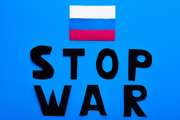 Vista dall'alto della bandiera russa e stop lettering guerra su sfondo blu  - Foto, immagini