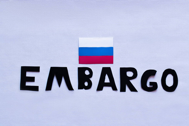 Vista dall'alto della bandiera russa e embargo lettering su sfondo bianco, guerra in Ucraina concetto  - Foto, immagini