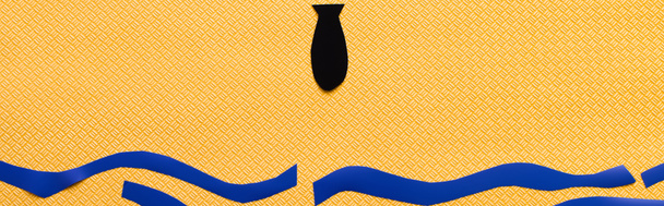 Вид сверху черной бумажной бомбы над морем на текстурированном желтом фоне, баннер  - Фото, изображение