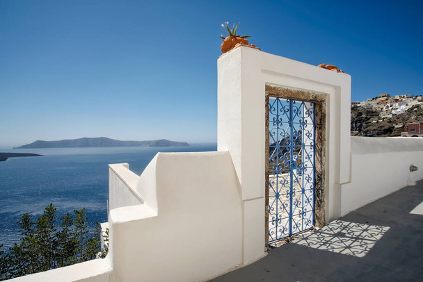 Зовнішні декоровані двері з квітковими рослинами на даху вілли і вид на море егейського моря в Фіра-Санторіні. - Фото, зображення