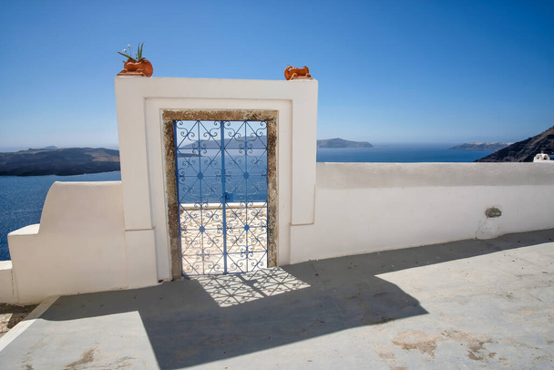 Eine Außentür mit Blumenpflanzen auf dem Dach einer Villa und Blick auf das Ägäische Meer in Fira Santorini - Foto, Bild