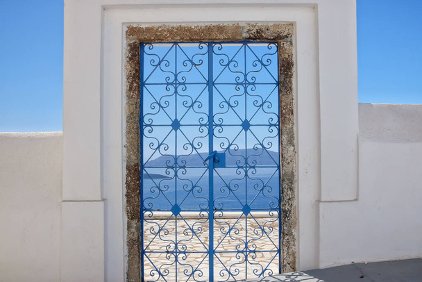 Una puerta exterior decorada con plantas de flores en el techo de una villa y vista al mar Egeo en Fira Santorini - Foto, imagen