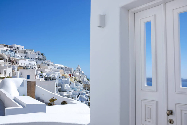 Jellemző design fehér dekorációs ajtó mellett egy sikátor, lélegzetelállító kilátás nyílik a falu Fira és az égei-tengeri Santorini - Fotó, kép