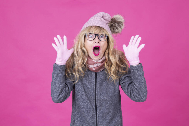 surprised woman in winter hat and gloves isolated on pink background - Foto, Imagem