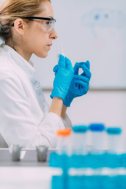 Test węchowy w laboratorium. Kobiety-naukowcy wyczuwają próbkę w szklanej kolbie.. - Zdjęcie, obraz
