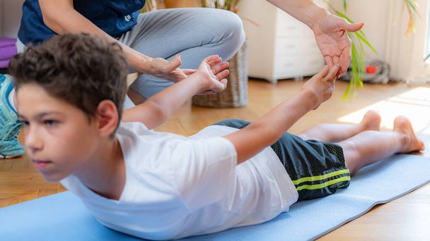 Lower back stretch. Boy exercising with physical therapist. - Photo, Image