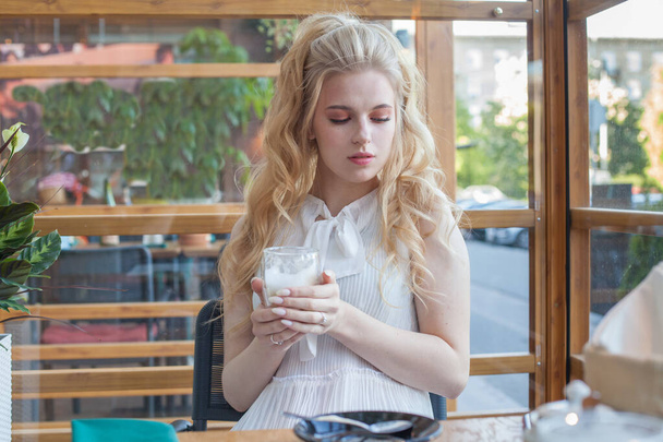 Σοβαρή νεαρή γυναίκα με αρωματικό καφέ στα χέρια της - Φωτογραφία, εικόνα