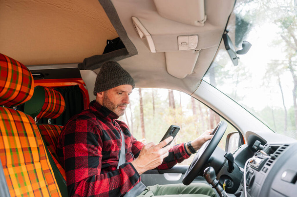 Adventurous man using smart phone in a van. - 写真・画像