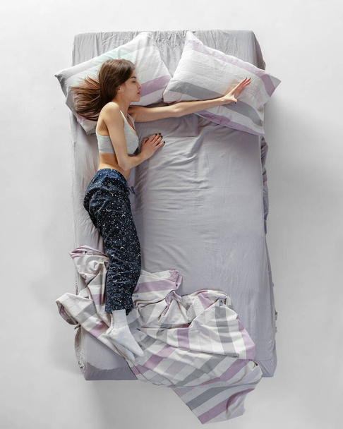 Top View muotokuva nuori tyttö yllään kotivaatteet, pyjama nukkuu iso harmaa sänky. Käsite terveys, kodin sisustus, rentoutumisaika, perhe, unelmat - Valokuva, kuva