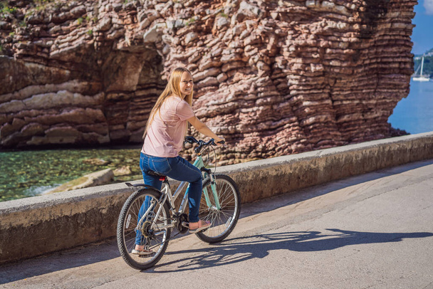 Woman tourist on a bicycle explores Budva in Montenegro. Cycling in Montenegro concept - Photo, image