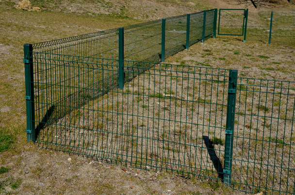 omheining met een bodem die is gemaakt van ingeklapte panelen als bescherming tegen wild. Het hek kan niet worden ondermijnd. nu zijn het huis en de tuin beschermd, een trainingsgebied voor honden met lage bescherming - Foto, afbeelding