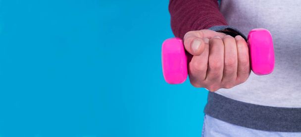 hand holding dumbbell on blue background - Foto, immagini
