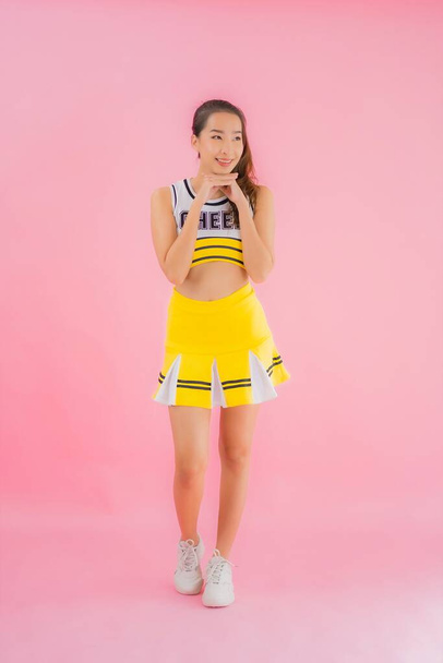 Portrait beautiful young asian woman cheerleader on pink isolated background - Foto, imagen