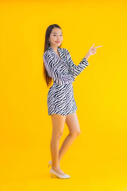 Portrait beautiful young asian woman smile happy with action on yellow isolated background - Zdjęcie, obraz