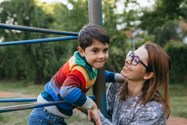 mother and son are playing outdoor on the playground in public park - Foto, afbeelding