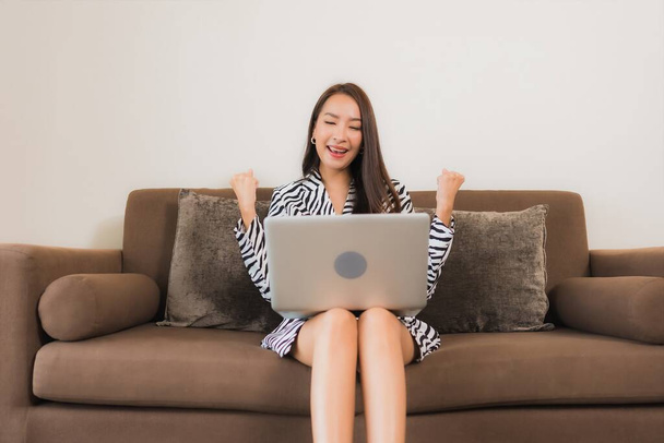 Retrato hermosa joven mujer asiática uso ordenador portátil en el sofá en la sala de estar área interior - Foto, imagen