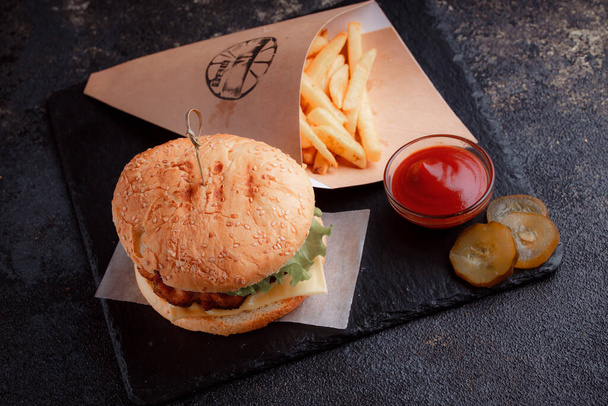Delicious homemade burger with grilled beef, tomato, cheese, cucumber and sauce on wooden table. - Foto, afbeelding