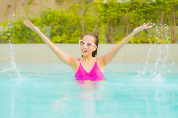 Retrato hermosa joven mujer asiática relajarse sonrisa alrededor de la piscina al aire libre en el complejo hotelero para vacaciones de viaje - Foto, Imagen