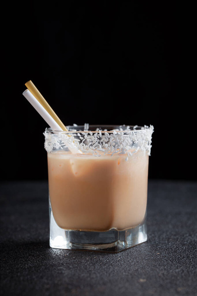 Light alcoholic drink with cream, liquor and vodka. A strong bar cocktail. Milkshake in a transparent glass goblet. - Fotó, kép