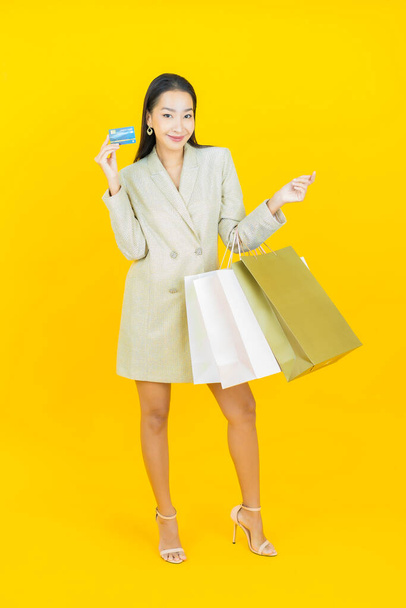 Retrato hermosa joven mujer asiática sonrisa con bolsa de compras en el fondo de color - Foto, imagen