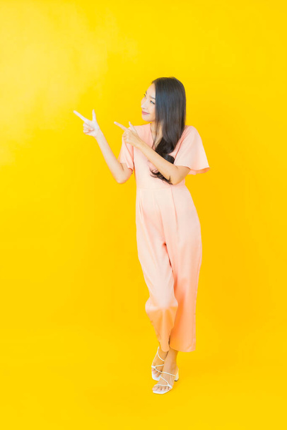 Ritratto bella giovane donna asiatica sorriso con azione su sfondo di colore - Foto, immagini