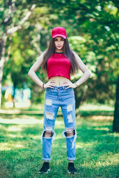 Червона шапка і тема. Красива серйозна дівчина з довгим волоссям. Літній стиль пішохідного одягу. Поняття особистої опіки. Щасливі емоції на обличчі
. - Фото, зображення