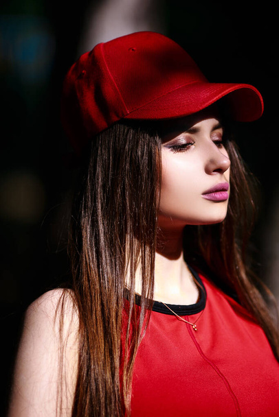 Red cap and the topic. Beautiful serious expression girl with long hair. Summer walking clothes style. The concept of personal care. Happy emotions on the face. - Foto, Imagem