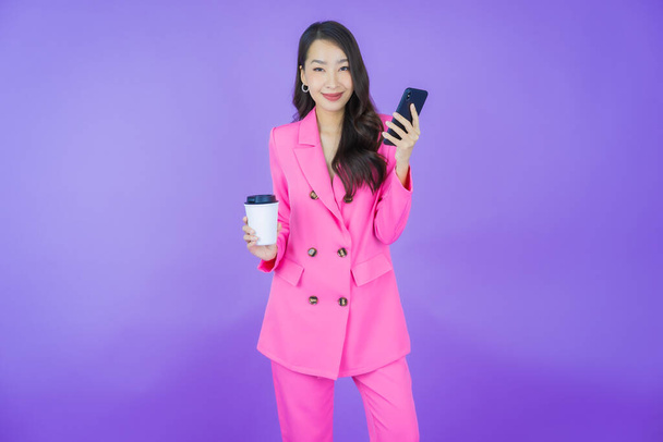 Portrait belle jeune femme asiatique sourire avec téléphone portable intelligent sur fond de couleur - Photo, image