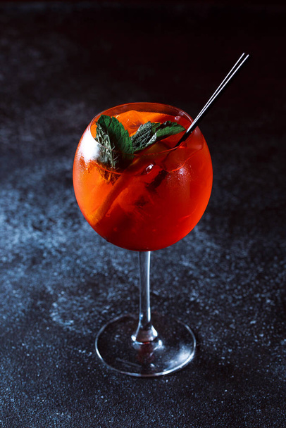 Alkoholický koktejl Aperol injekční stříkačka. Osvěžující koktejlový nápoj s pomerančem a mátou na tmavomodrém pozadí. - Fotografie, Obrázek