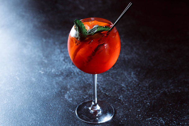 Strzykawka z alkoholem Aperol. orzeźwiający napój koktajlowy z pomarańczą i miętą na ciemnoniebieskim tle. - Zdjęcie, obraz