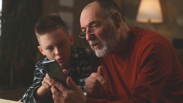 Kleinzoon leert grootvader om smartphone te gebruiken - Foto, afbeelding