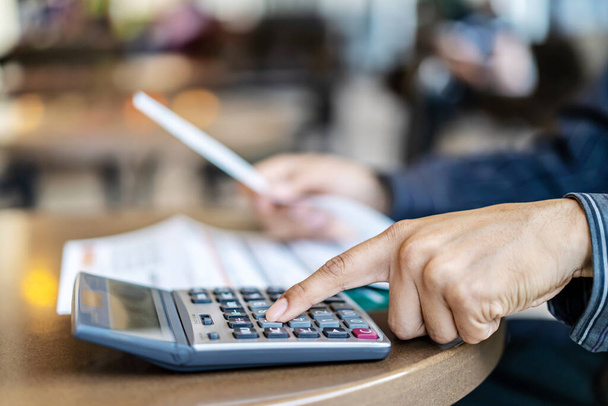 Könyvelési üzletemberek nyomja a számológép kiszámítani a különböző költségeket, hogy ki kell fizetni a számlát, Sok számlát tartott és elhelyezett az asztalon, Pénzügyi és adórendszer koncepció. - Fotó, kép