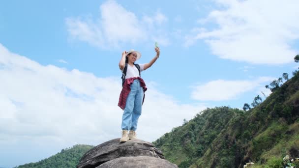 Hipster žena v klobouku relaxační v přírodě na dovolené a přičemž selfie s chytrým telefonem na horském pozadí. - Záběry, video
