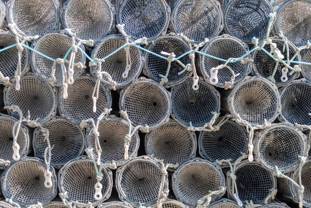 Hromada cylindrických pastí na kraba nebo humra uložených na molu v přístavu Aberystwyth. Pasti jsou vidět zakončit vytvořením vzoru kruhů a lan - Fotografie, Obrázek