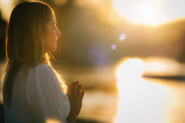 Mulher a meditar junto ao lago. Posição de oração.   - Foto, Imagem