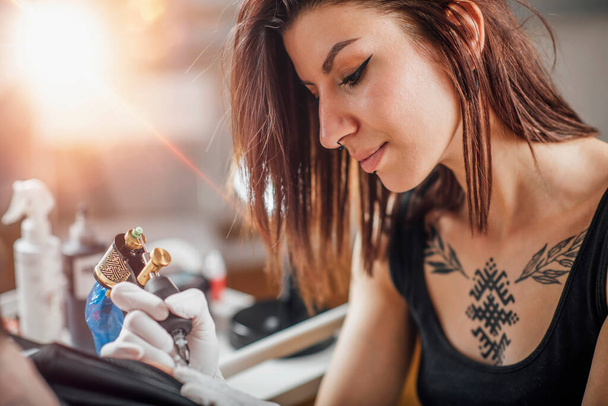 Kobieta tatuaż artysta tatuaż mans ramię w studio  - Zdjęcie, obraz