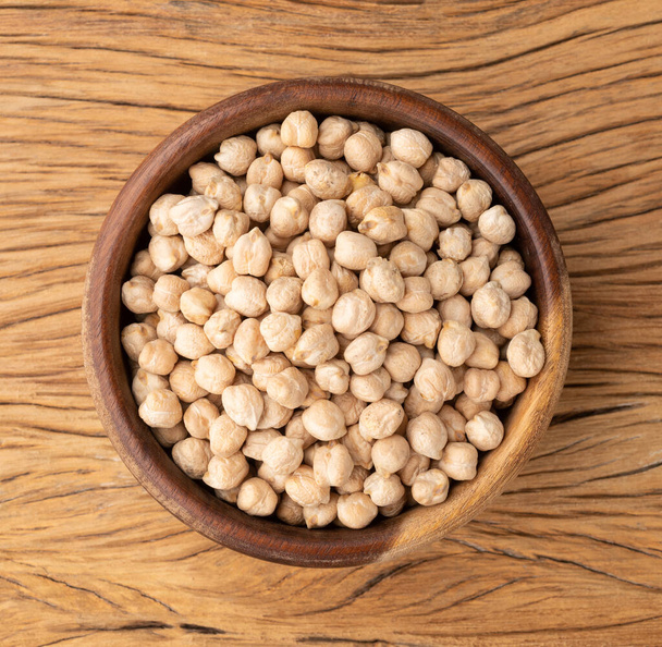 Raw chickpeas on a bowl over wooden table. - Photo, Image
