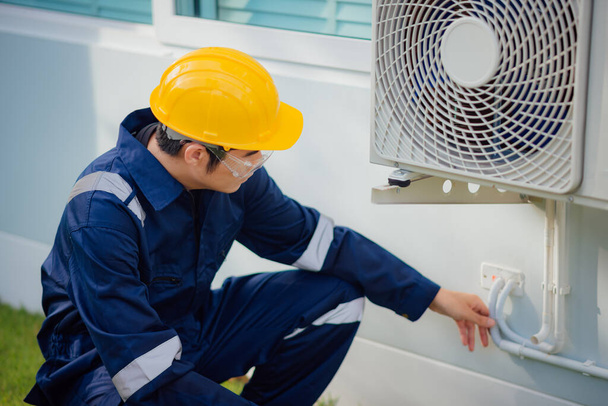 Muž technik kontroluje chladící potrubí klimatizátoru vzduchu venku. - Fotografie, Obrázek