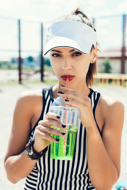 Sporty woman drinking water against the sportsground - Foto, imagen