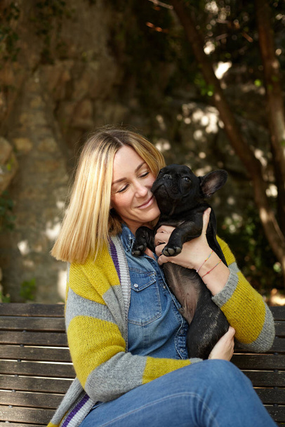 happy young woman with french bulldog dog sitting on a bench outdoor - Zdjęcie, obraz